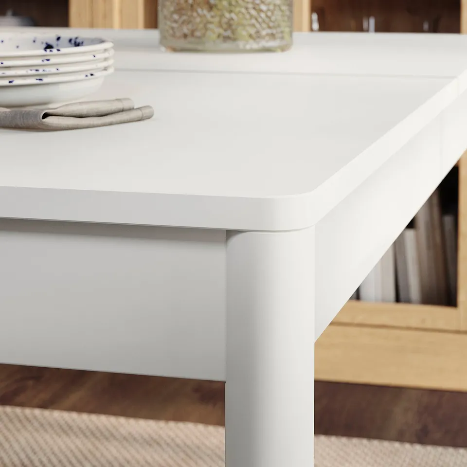 Modern white dining table with neat edges, showing off clean lines and sturdy legs, ready for a meal.