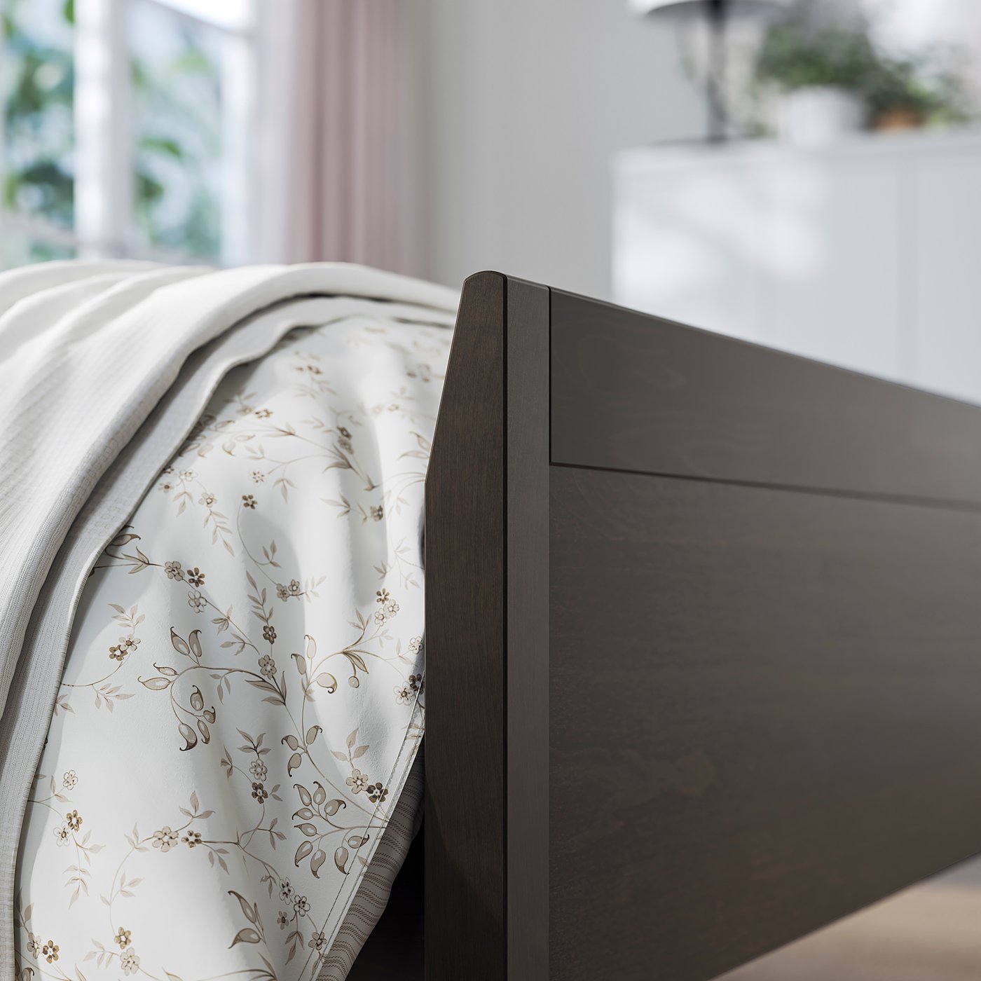 Modern bed with a dark wooden frame and white floral bedding.