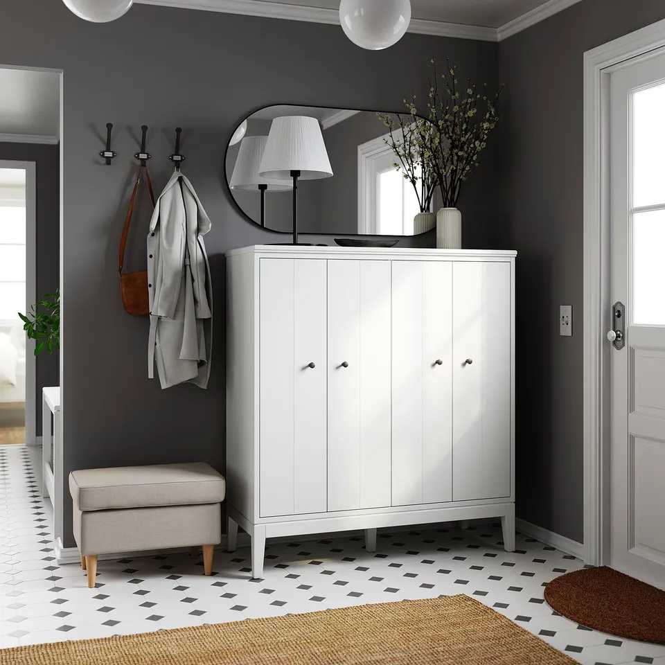 Modern entryway with white IDANÄS cabinet, grey walls, coat hooks, lamp, mirror, and patterned rug.