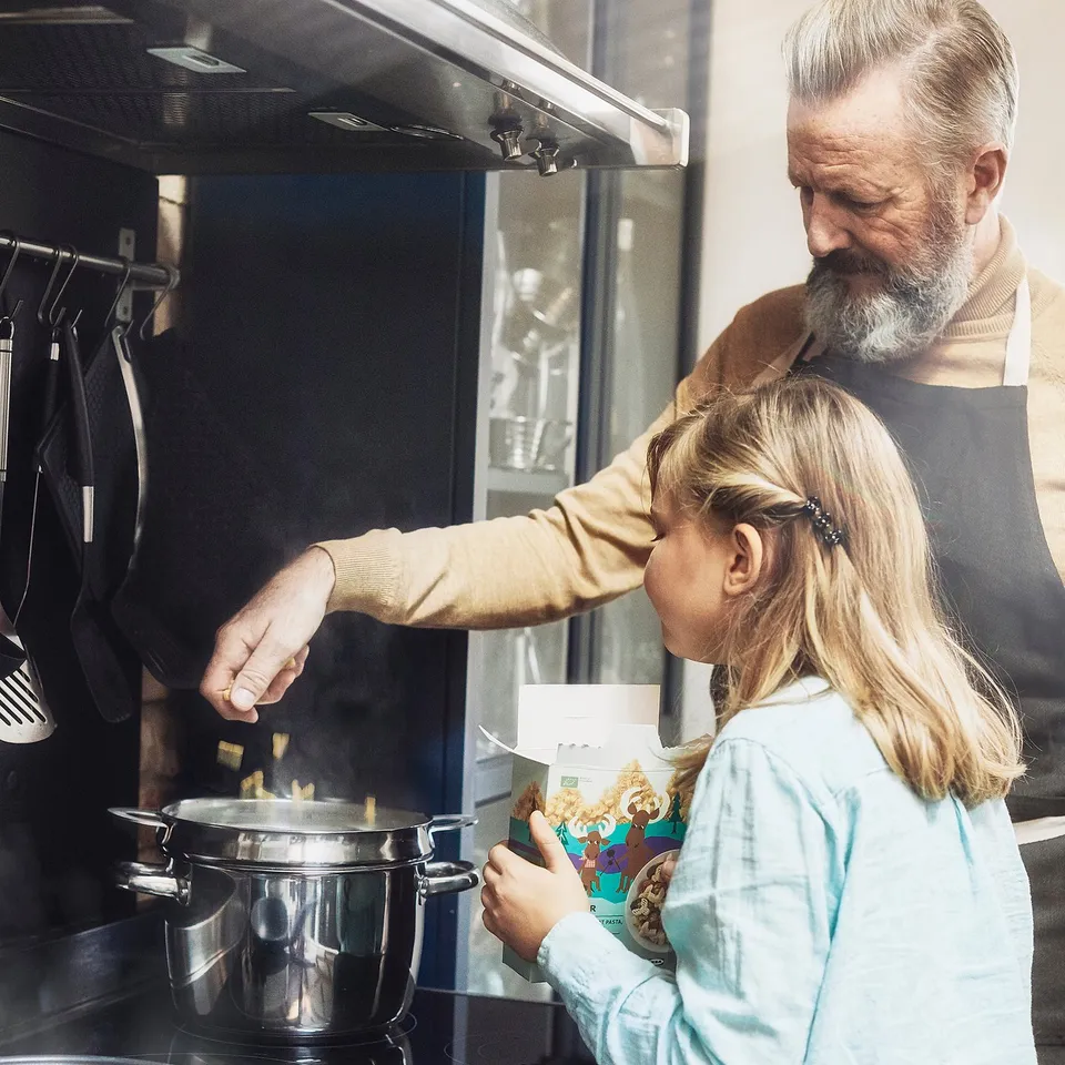 An adult and child cook moose-shaped pasta on the stove, from a box labelled BÄSTISAR.