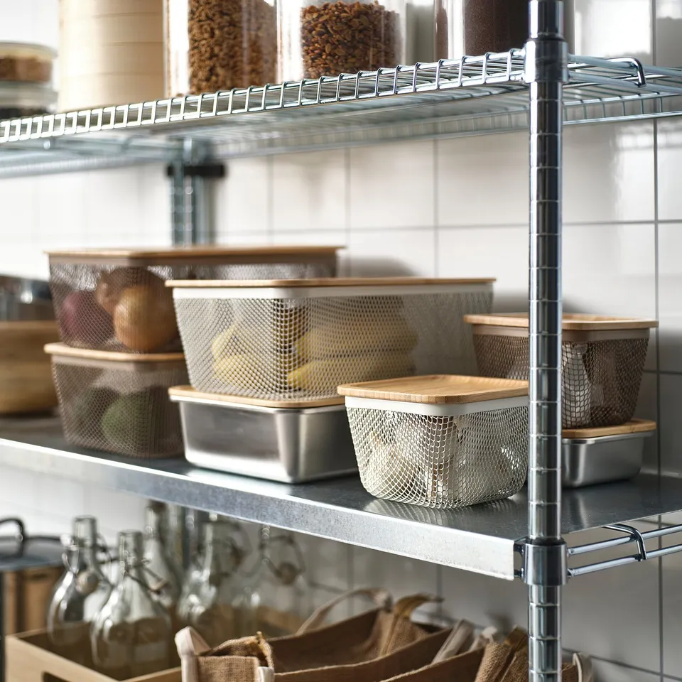 Metal shelves with mesh baskets holding fruits, veggies, grains, and bottles.