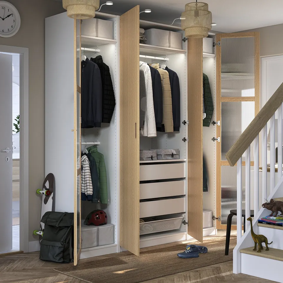 Modern closet with adjustable feet, slow-close hinges, and lighting. Organised clothes, bags, helmets; staircase with toys.