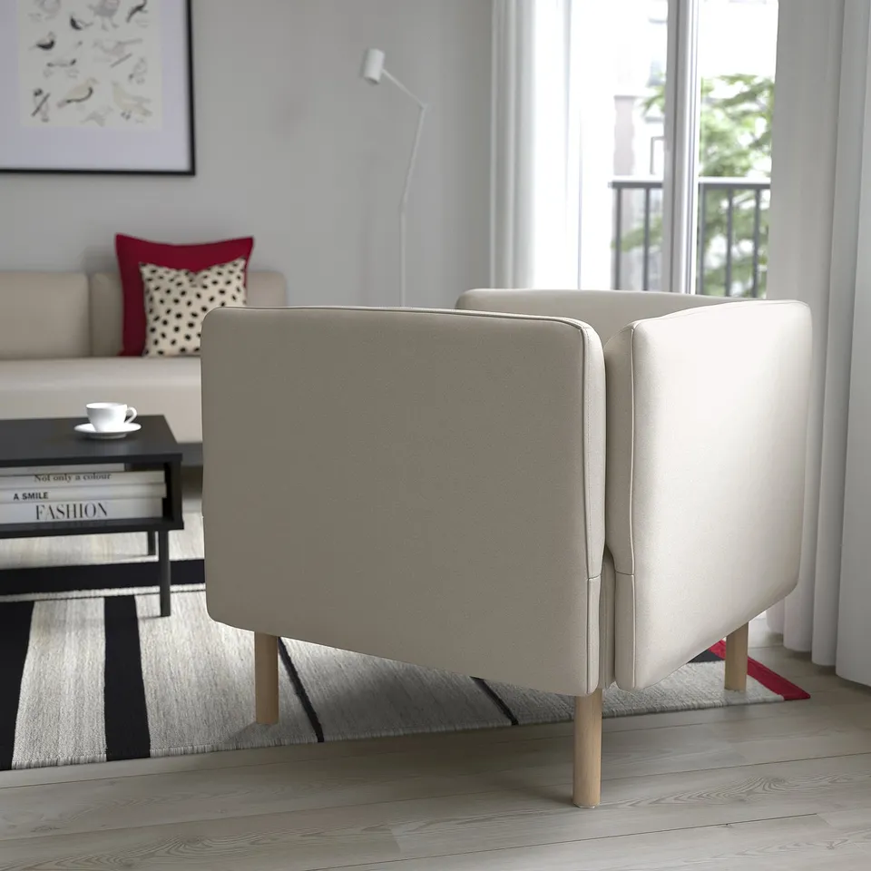 A modern living room featuring a beige LILLEHEM modular sofa with wooden legs near a large window, providing bright natural light.