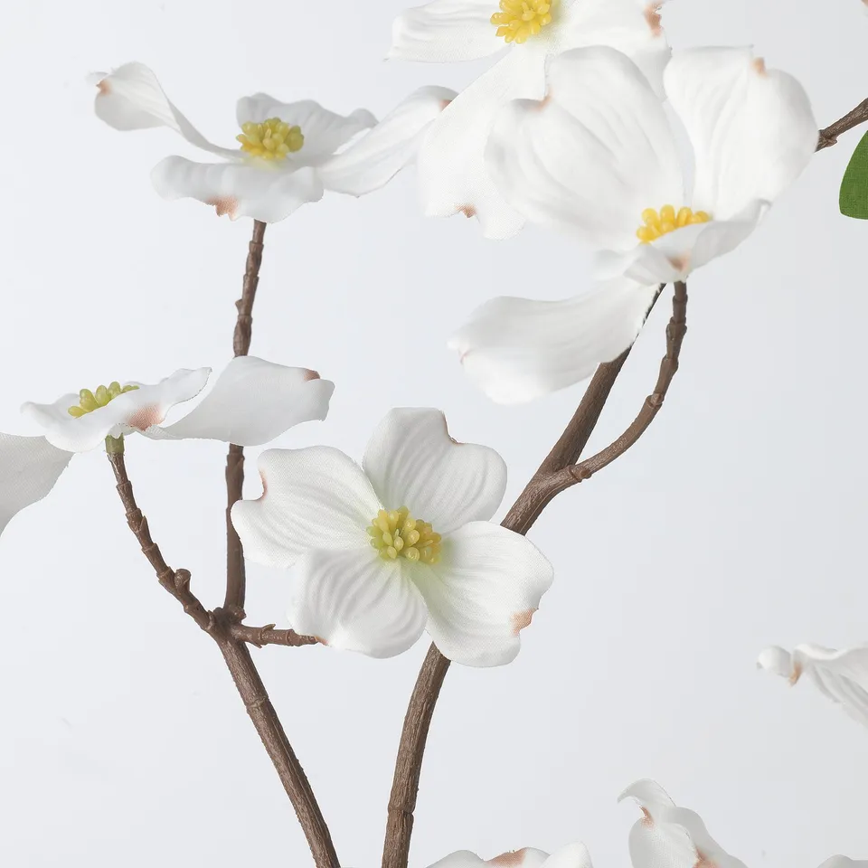 Artificial white dogwood flowers on branches. Realistic petals and yellow centres.