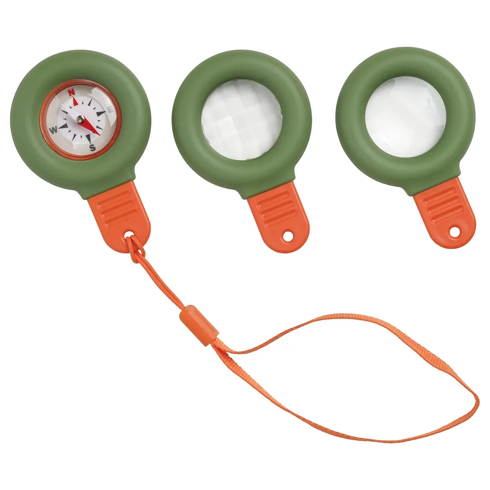 Three green compass toys with orange handles and strings. One shows a compass face, two are blank. Bright, kid-friendly design.