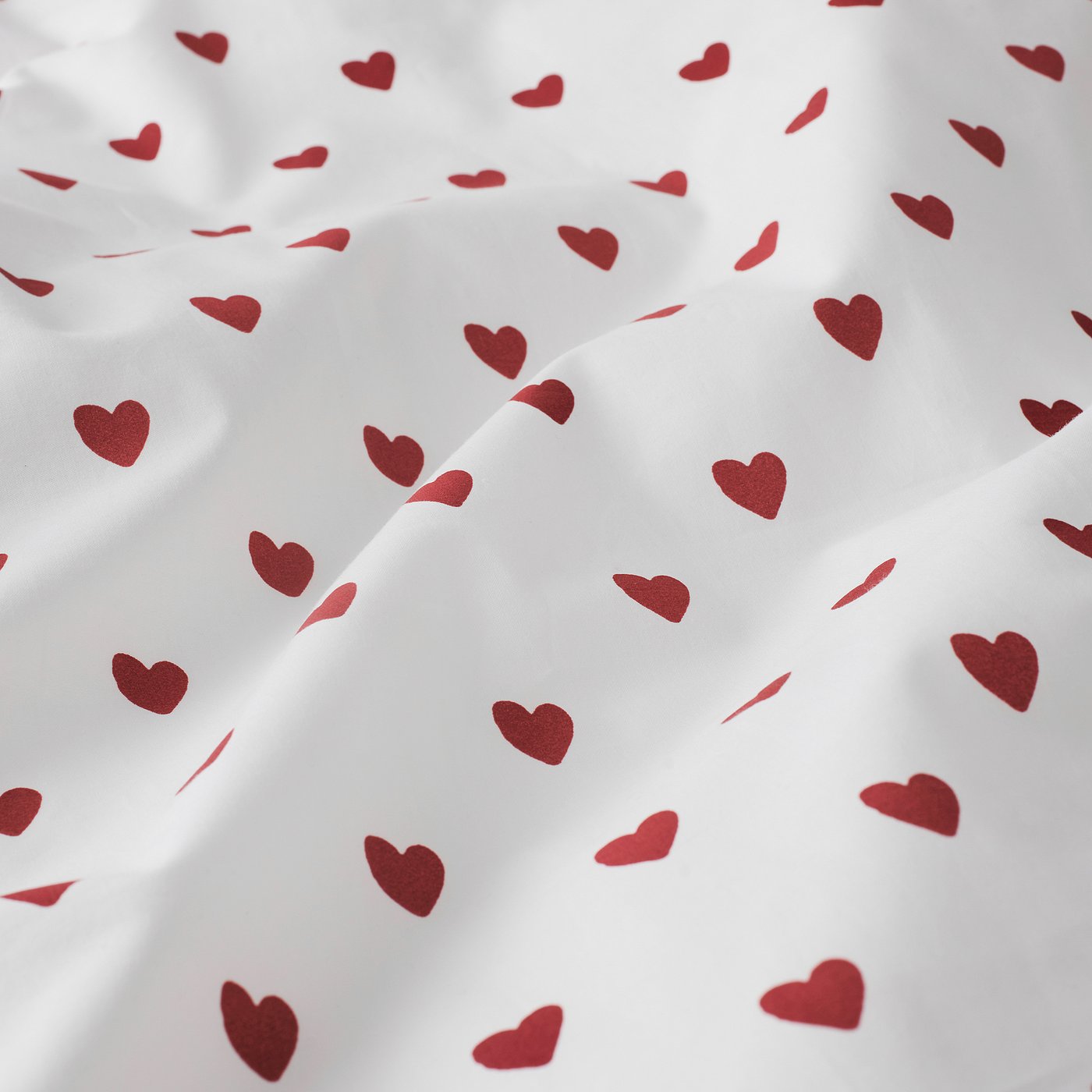 White duvet cover with scattered maroon hearts, showing soft, comfy cotton fabric with neat, even stitching.