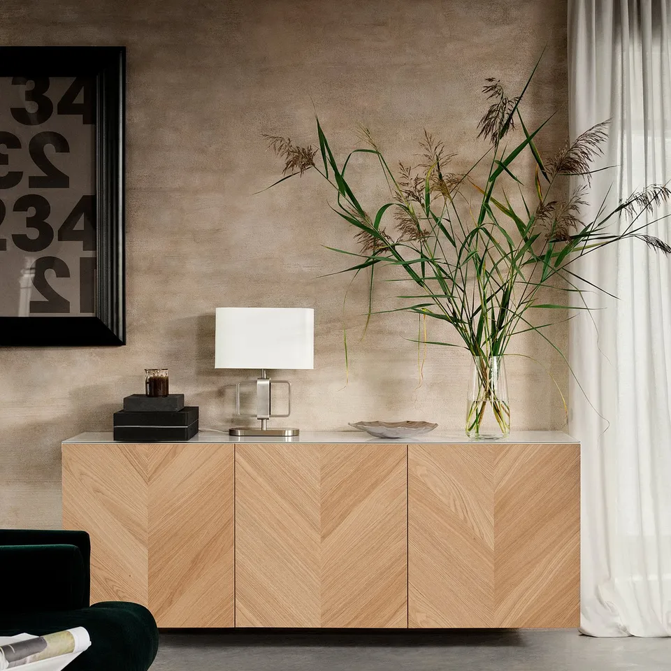 Natural oak wooden cabinet with white lamp and tall plant, modern decor.