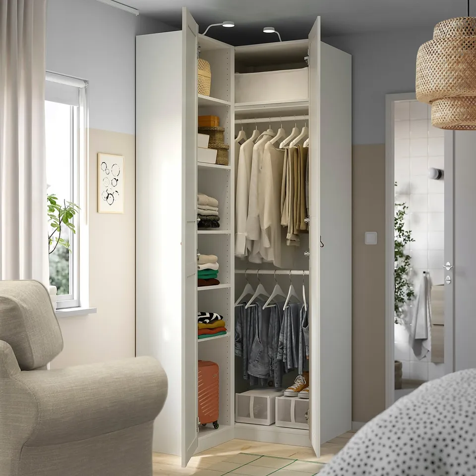 Open wardrobe with hanging clothes. Shelves have folded clothes and basket. Integrated lighting inside.