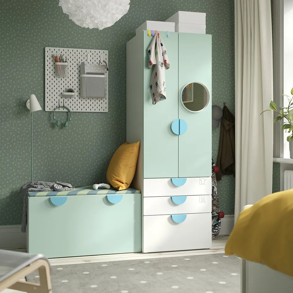 Kid's room with SMÅSTAD: light mint wardrobe, drawers, bench, pegboard, yellow pillow, grey rug, coat rack, and lamps.