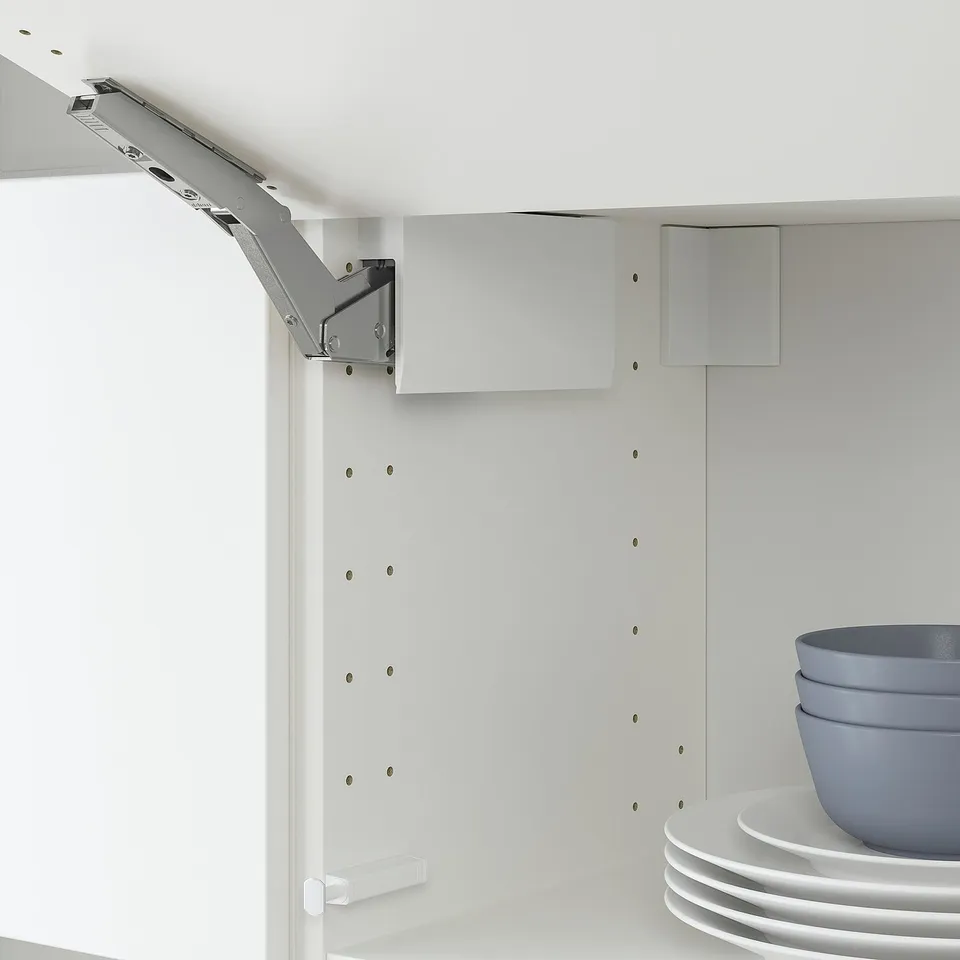 White cabinet hinge, adjustable, with soft-close mechanism. Aligned doors and drawers, modern kitchen feature.