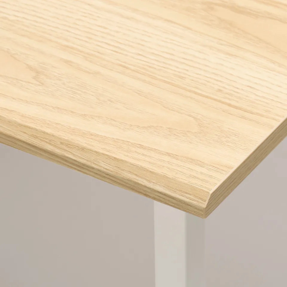 Close-up of a sleek, light-colored wooden tabletop with a smooth, bevelled edge, showcasing its quality finish.