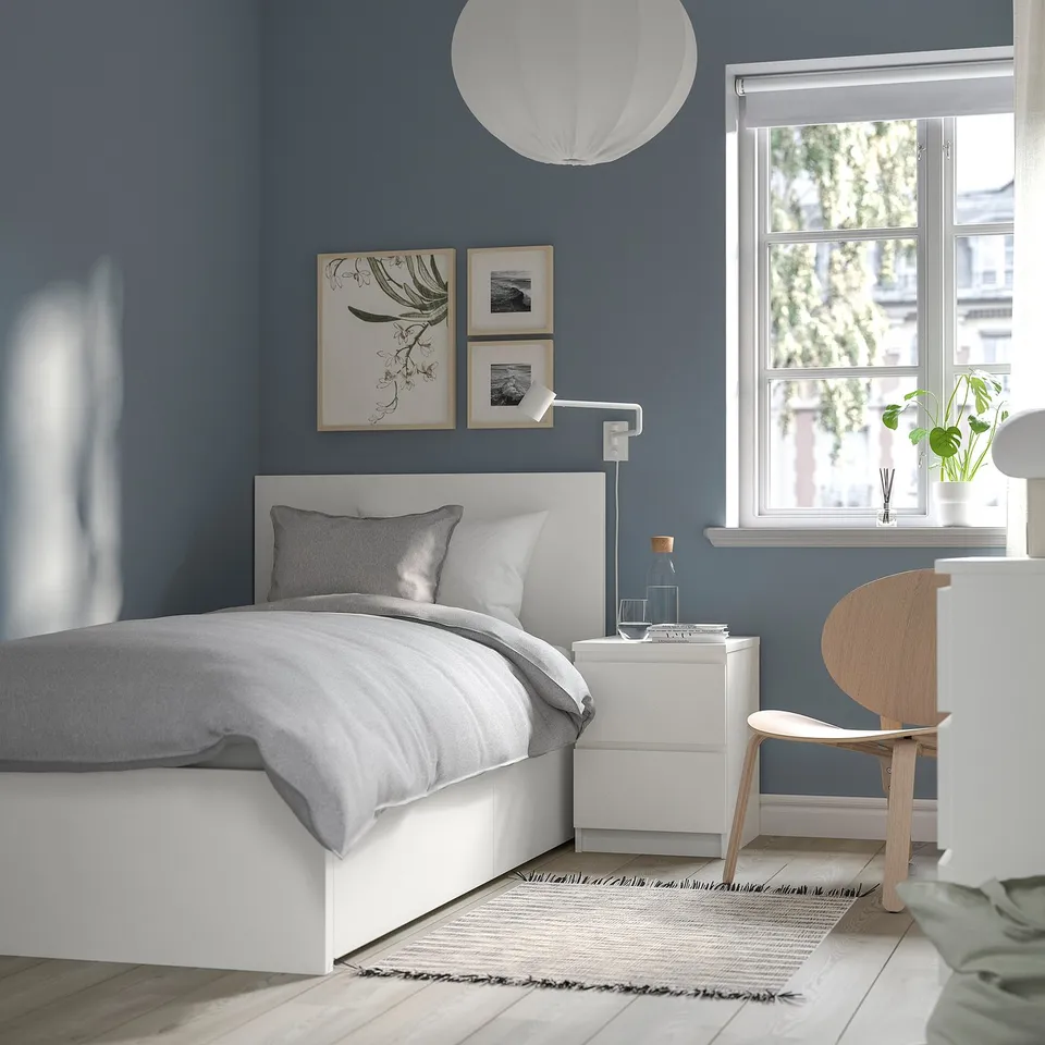 Modern bedroom with MALM bed, grey pillows, blue wall, art, bedside table, chair, rug, pendant lamp, calming colours.
