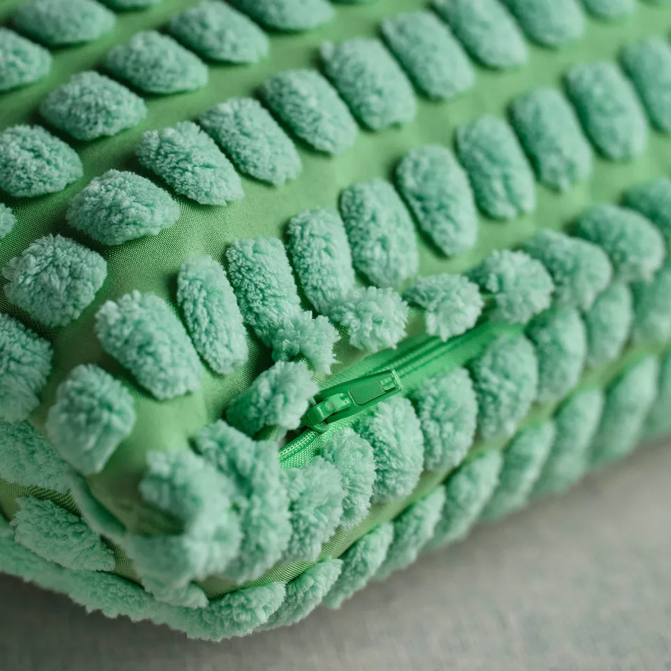 Close-up of soft, textured green cushion cover with visible zip, showcasing quality craftsmanship.