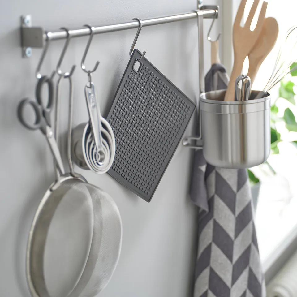 Kitchen rack with tools: scissors, cups, strainer, holder, utensils, towel.