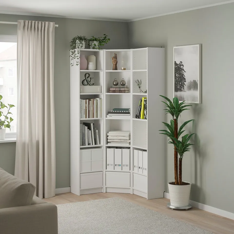 White corner bookshelf with books, vases, and plants.