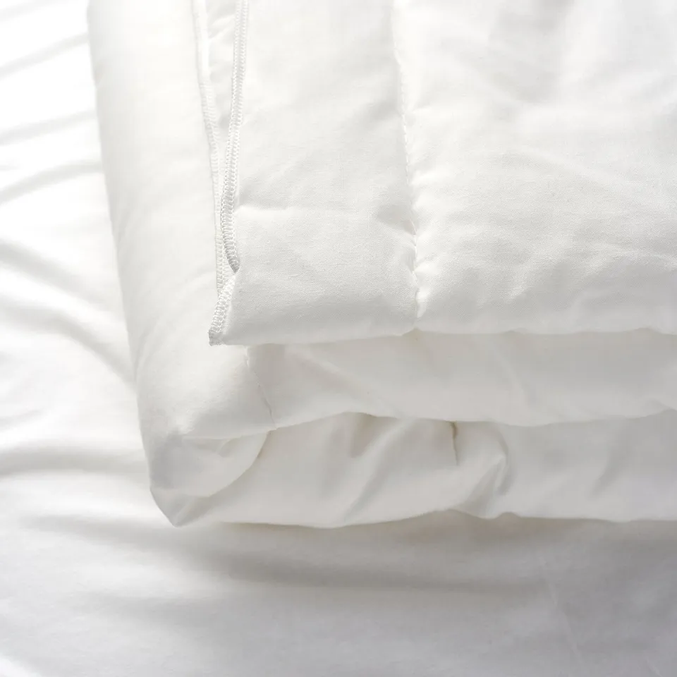 A close-up of a soft, white duvet with well-sewn edges, showcasing its fluffy texture and high-quality fabric.