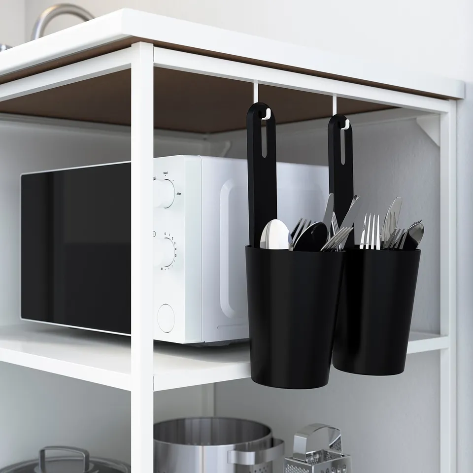Kitchen shelf with microwave, hanging hooks, and utensils in containers.