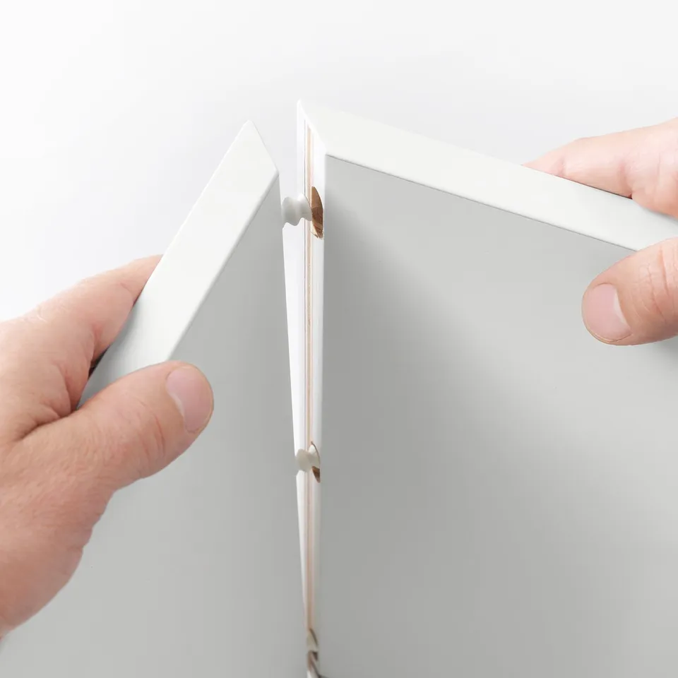 Hands adjusting wall-mounted glass storage cube.