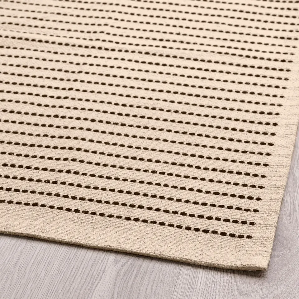 Modern rug with natural tones and black stripes, showcasing high-quality cotton weave, ideal for any room.