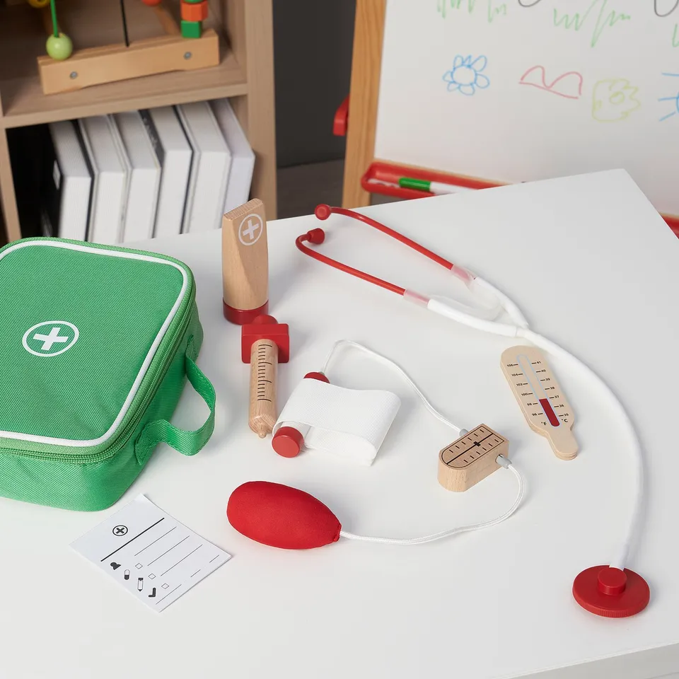 A childrens medical play set including a stethoscope, syringe, and other tools in a green bag for imaginative doctor role-play.