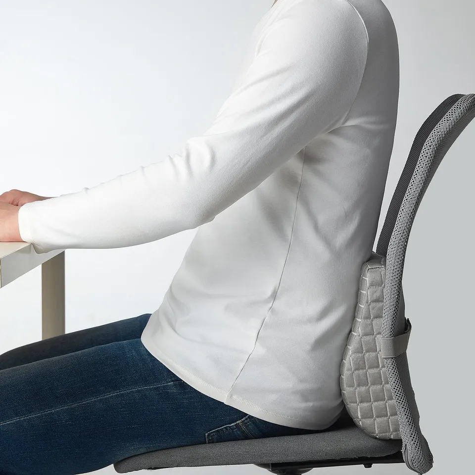 Person sitting in chair with lumbar cushion, featuring gel side for cooling, supporting back.
