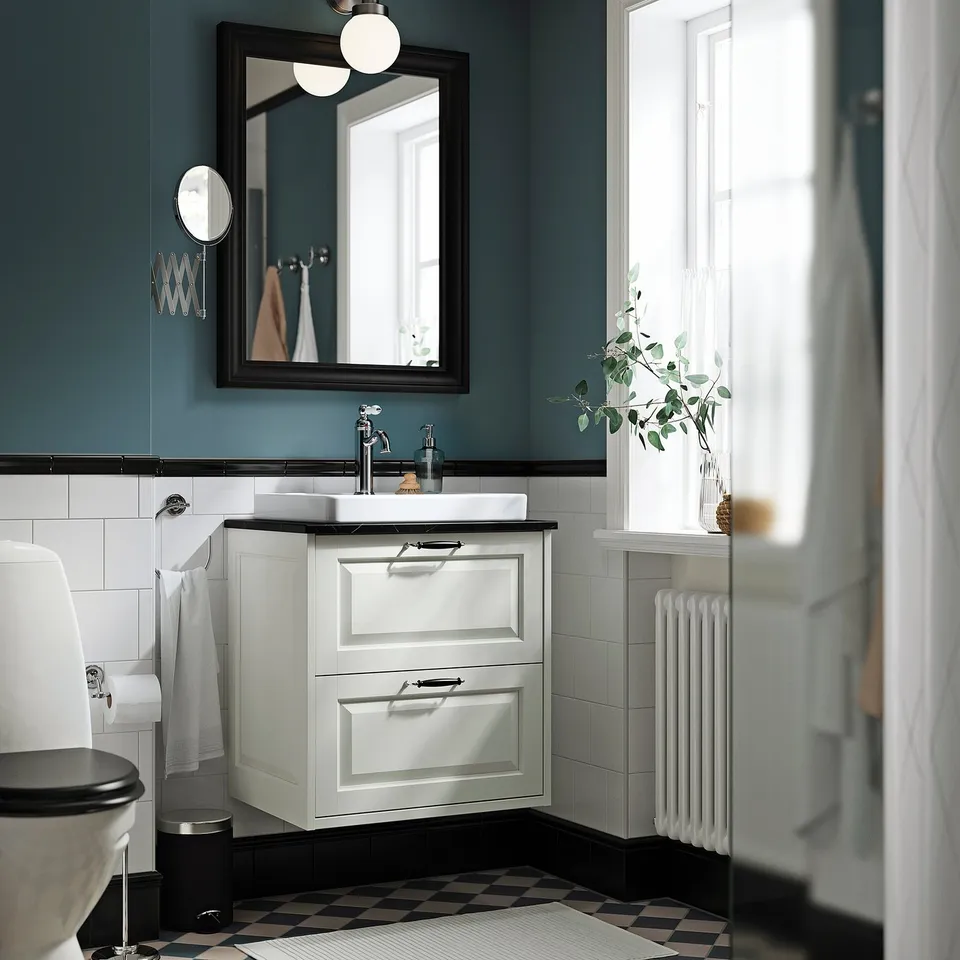 Modern bathroom with TÄNNFORSEN white cabinet, large mirror, green walls, black floor tiles, and white radiator.