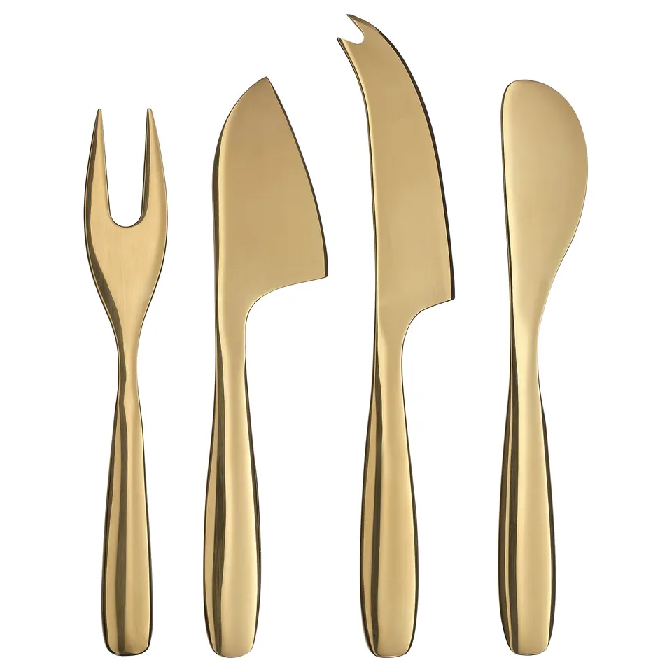 Brass-colored kitchen utensils set: fork, spatula, knife, cheese knife. Stainless steel for durability. Festive table setting.