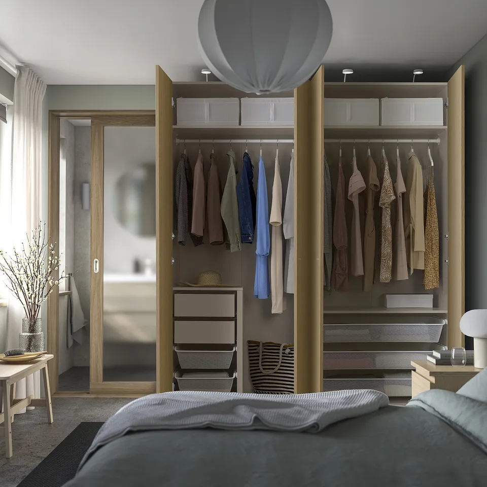 Modern bedroom with grey bed and open PAX wardrobe, showing organised storage.
