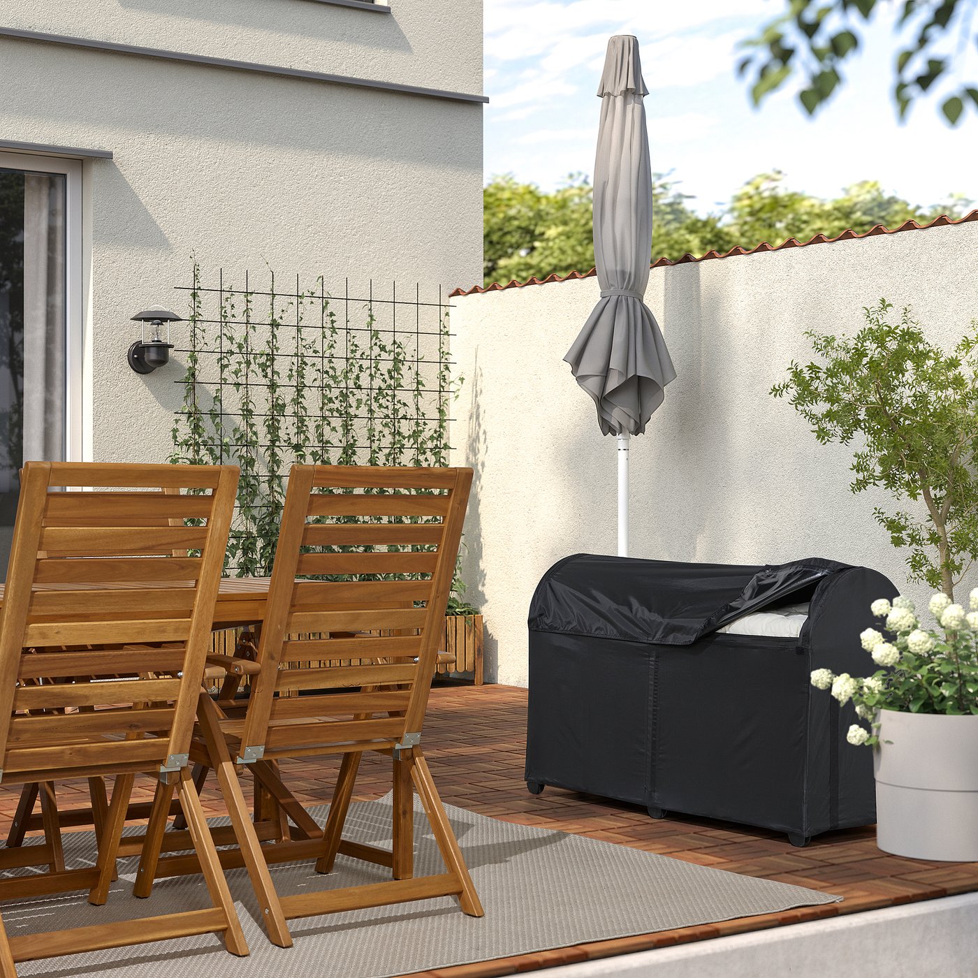 Wooden patio set with umbrella and storage box for cushions, surrounded by plants.