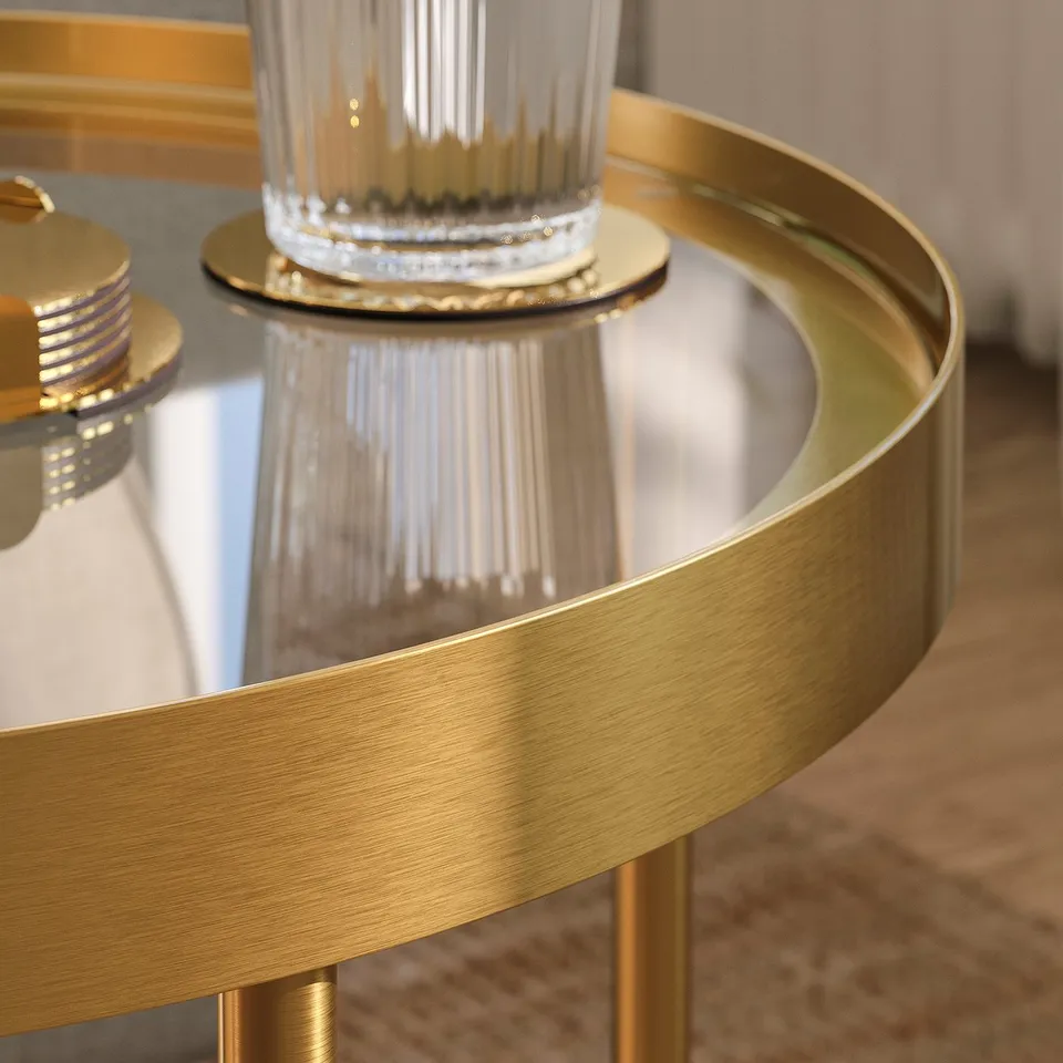 Modern gold side table with glass top, elegant design, reflective surface.