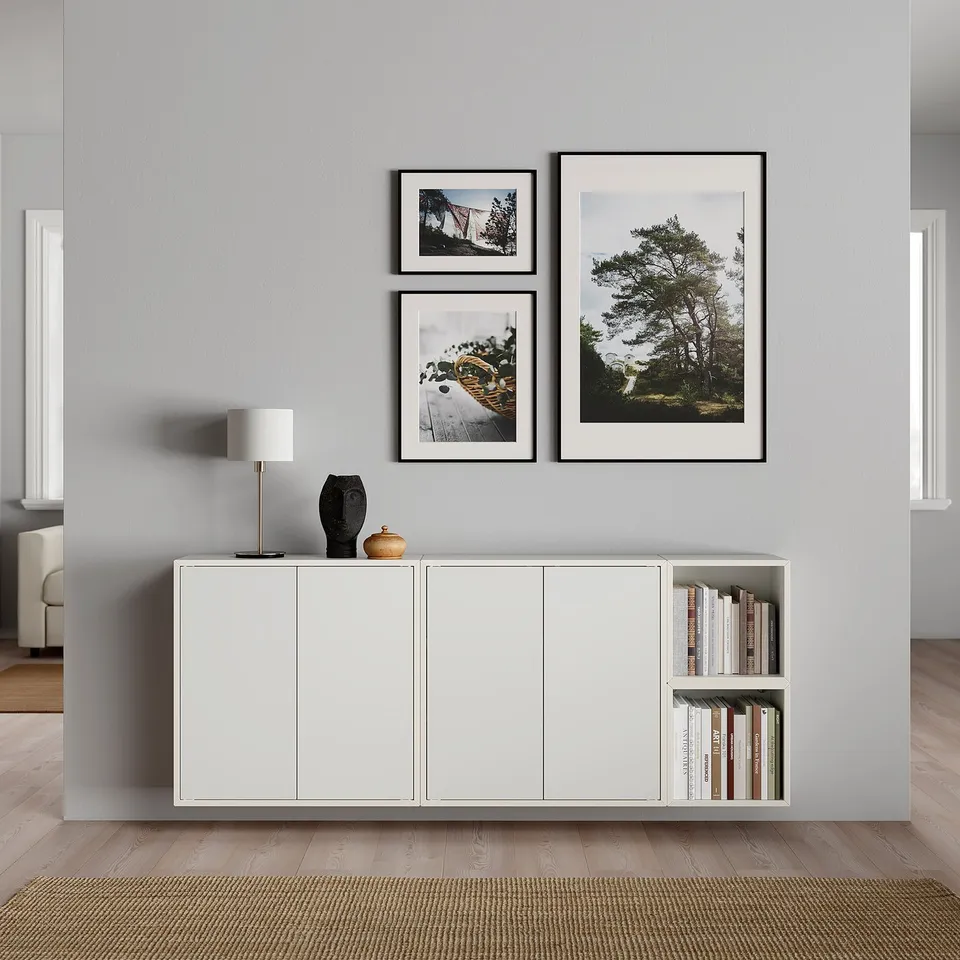 Modern living room setup featuring a white EKET storage unit with books and decorative items on top. Three framed nature photos hang above.
