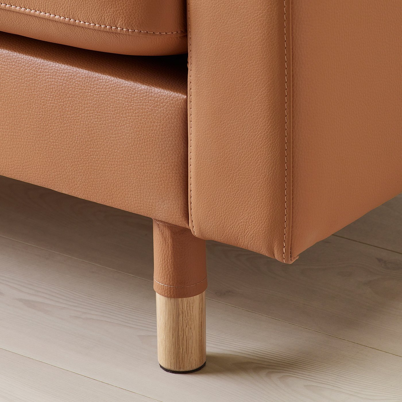 Close-up of a tan leather sofa leg, showcasing high-quality materials and craftsmanship.