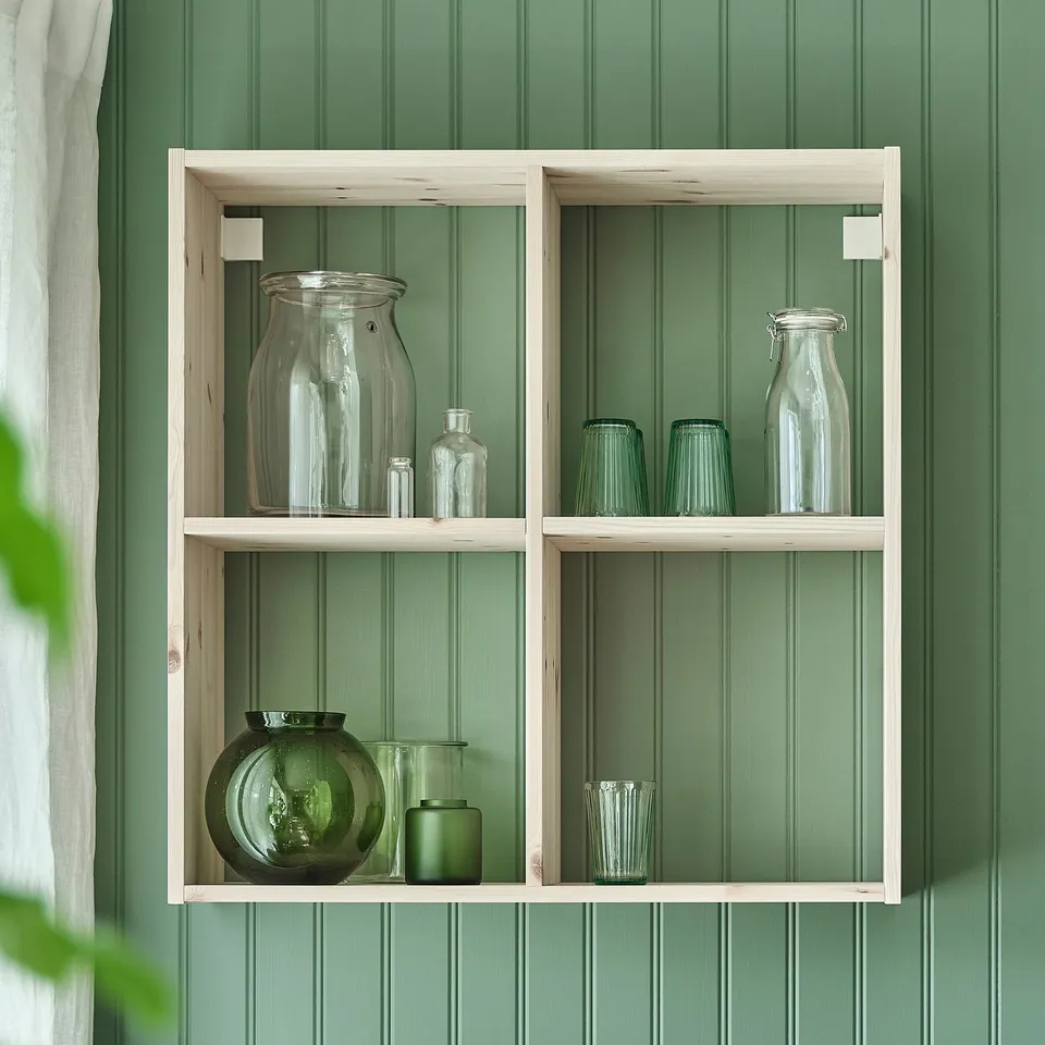 Wooden shelf with KORKEN jars in sizes & colours against green wall.