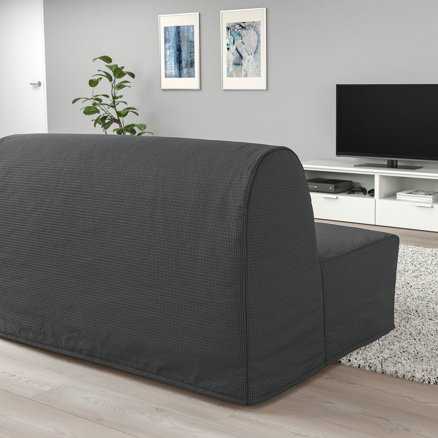 Black sofa-bed in minimalist living room with tv and art.