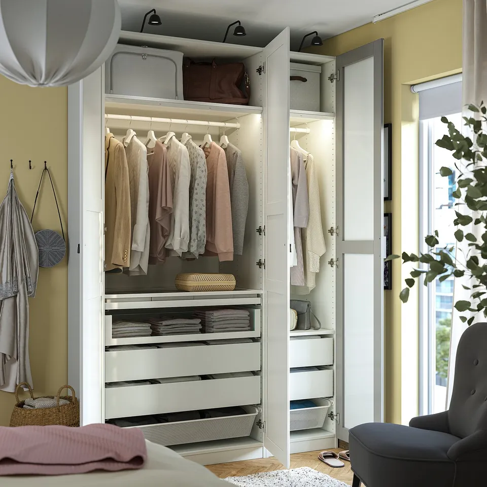 Modern wardrobe with hangers, drawers, and lighting, displaying neatly organised clothes and accessories.