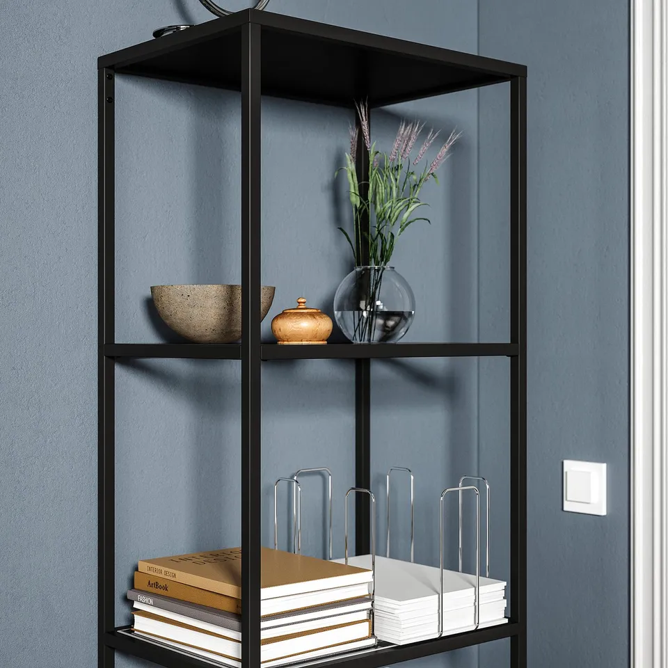 Black metal bookshelf with glass accents, holding vases, bowls, books, and paper organisers against a blue wall.