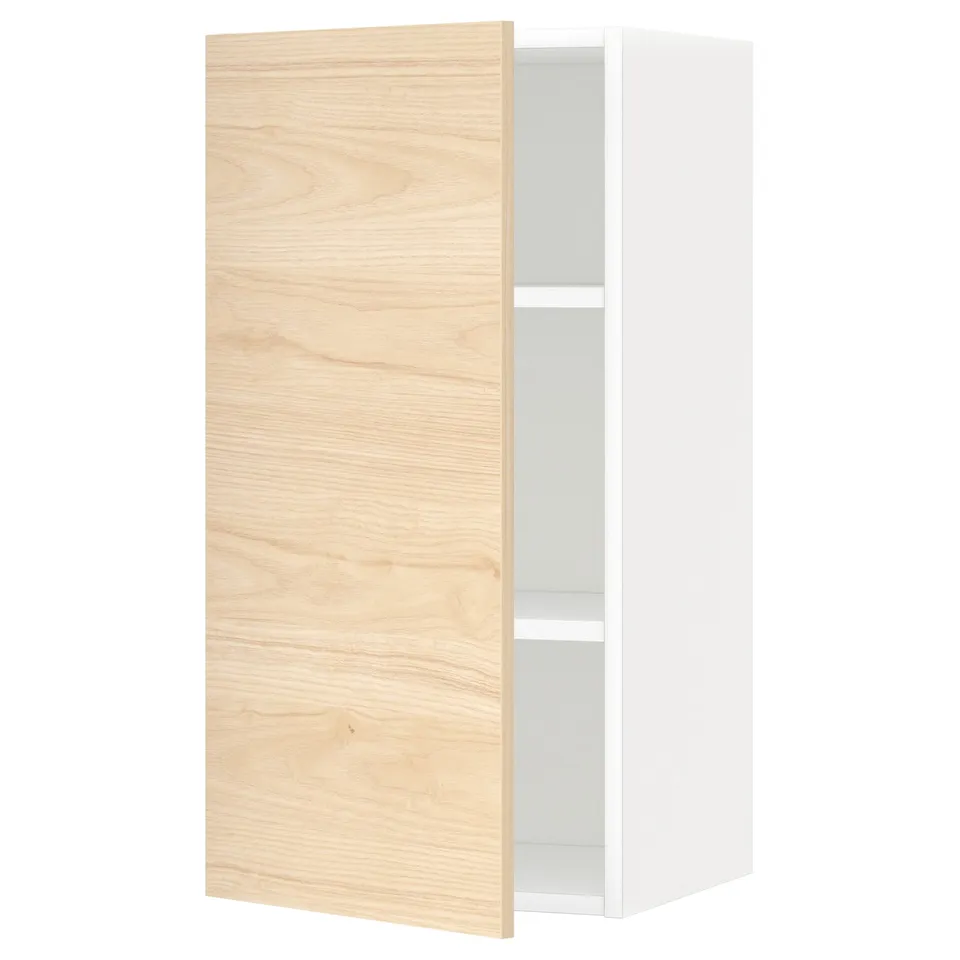 A white METOD kitchen wall cabinet with a light ash wood door partially open, revealing an adjustable shelf inside.
