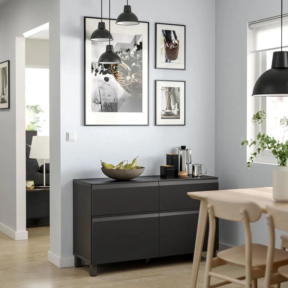Modern dining area with BESTÅ black sideboard, wooden table, chairs, and wall art.