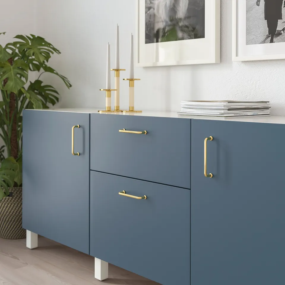 Blue cabinet with gold handles, two drawers, a door, and decorative items on top.