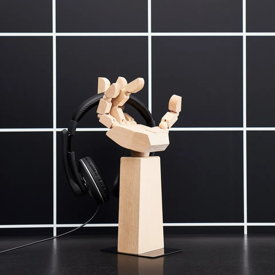 Wooden headphone stand, LÅNESPELARE, light brown, adjustable fingers, holds black headphones, modern minimalist design.