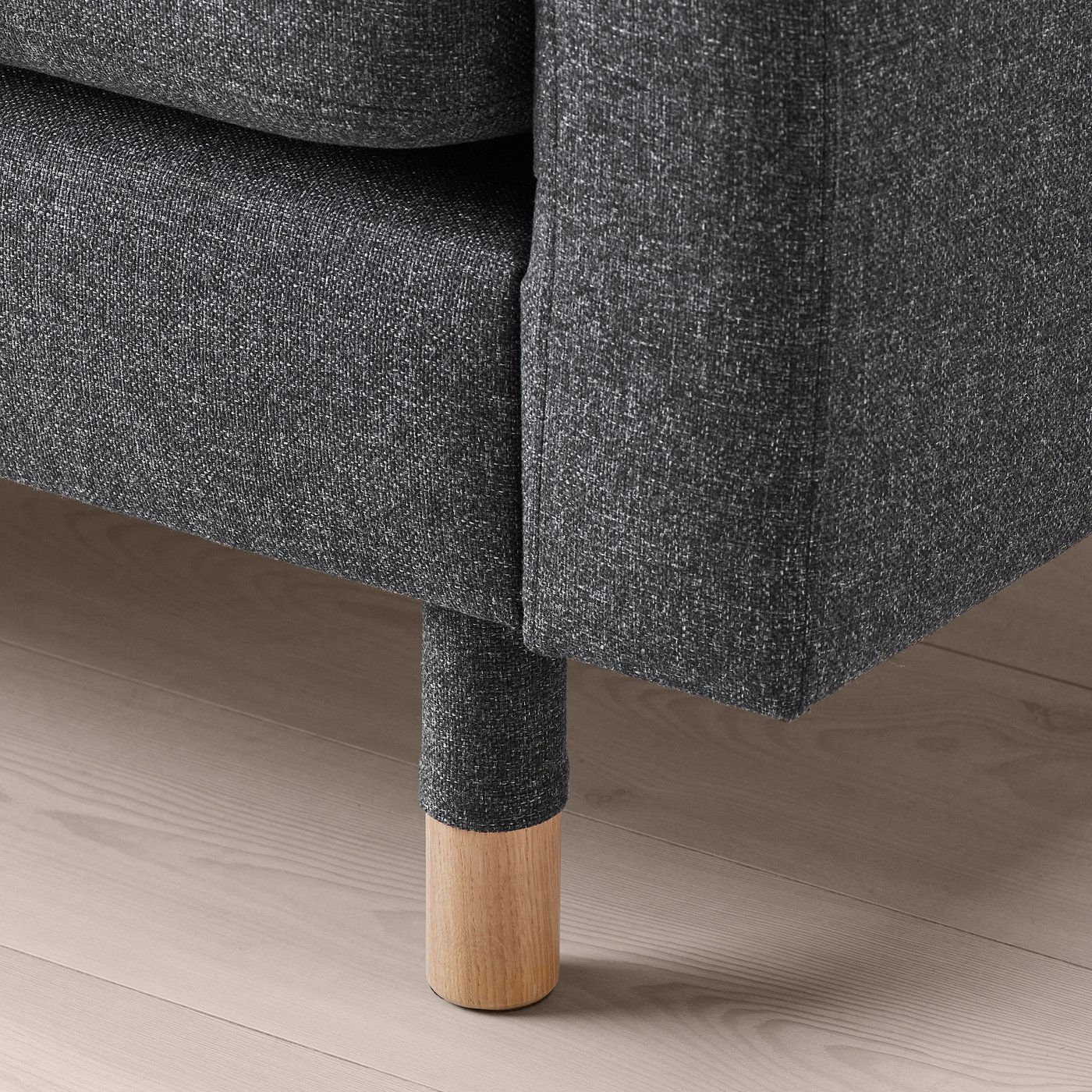 Close-up of a stylish, dark fabric-covered armchair with wooden legs.