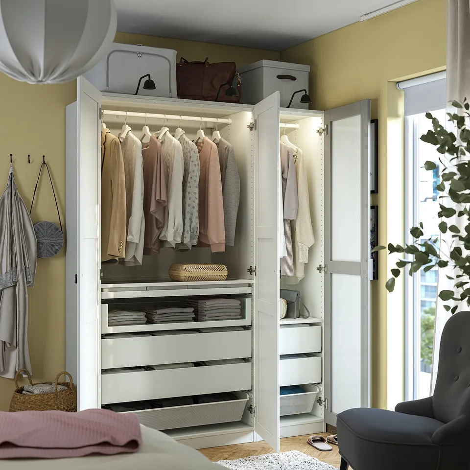 White PAX wardrobe with mirrors, hangers, shelves, drawers, and internal lighting organises clothes neatly.