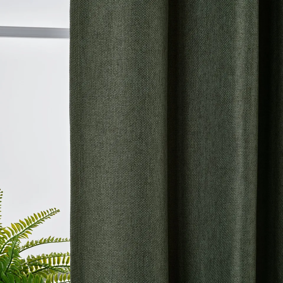 Dark green room-darkening curtains hang by a window, providing privacy and blocking sunlight.