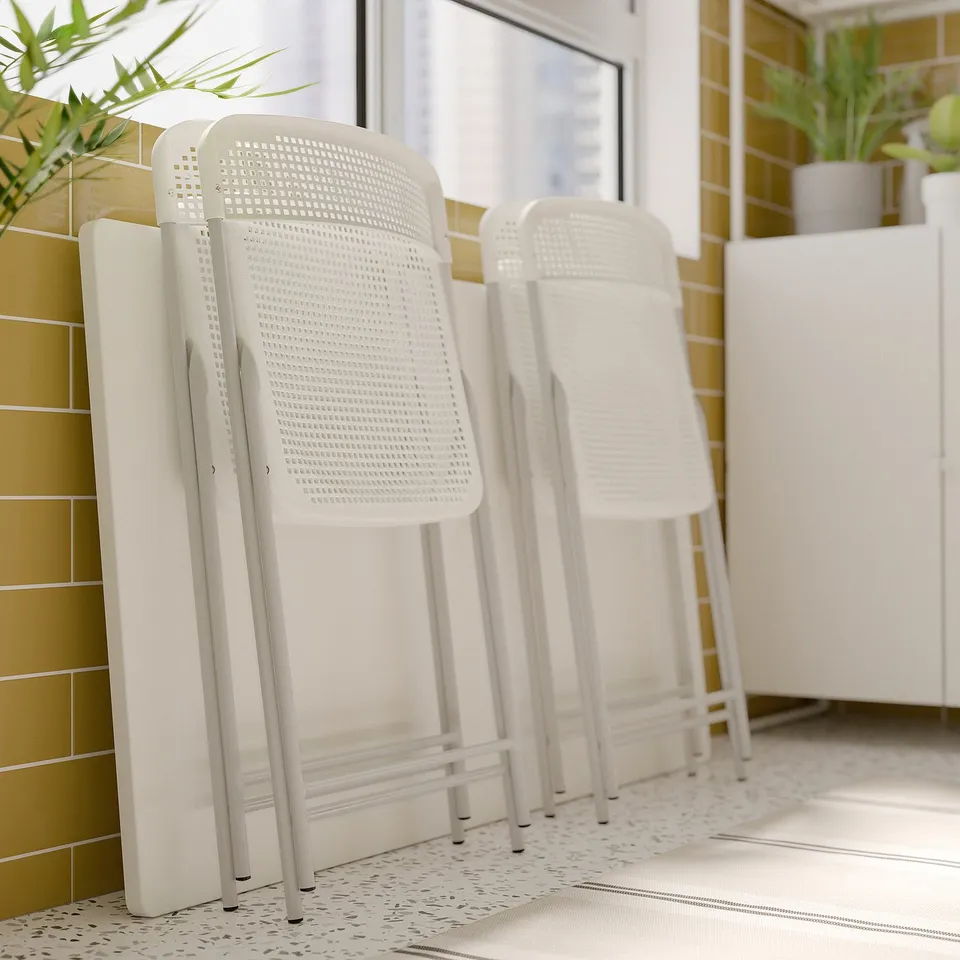 Three white torparo chairs, plastic and metal, folded, modern design, indoor setting.