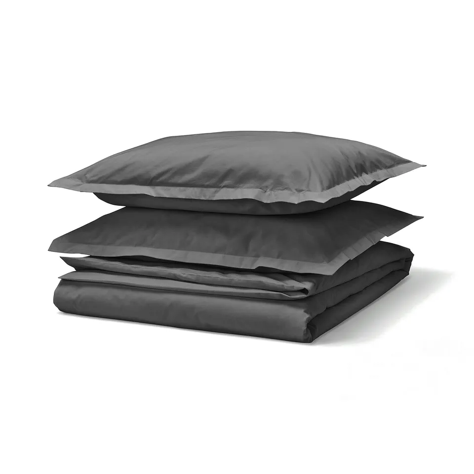 Dark grey bed sheet set, folded, on white background. Made of cotton.