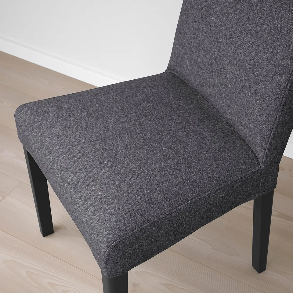 Modern dark grey upholstered chair with sleek legs on light wooden floor.