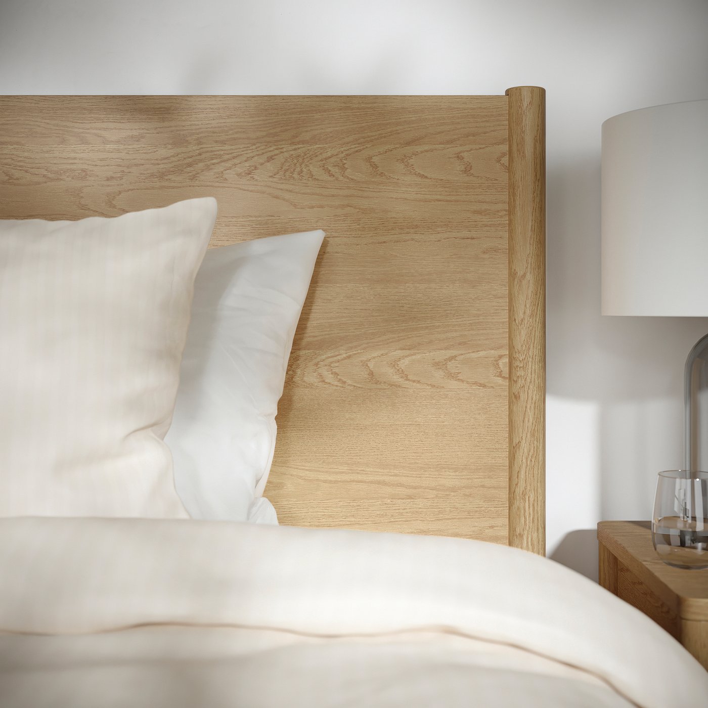 Minimalist bed with wooden headboard, plush white pillows & stylish bedside lamp.