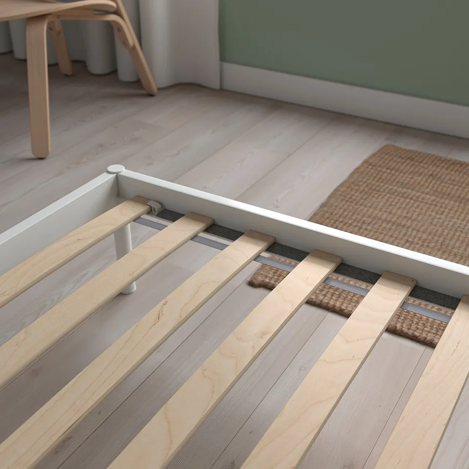 Wooden bed frame with screws, wheels, and storage space.