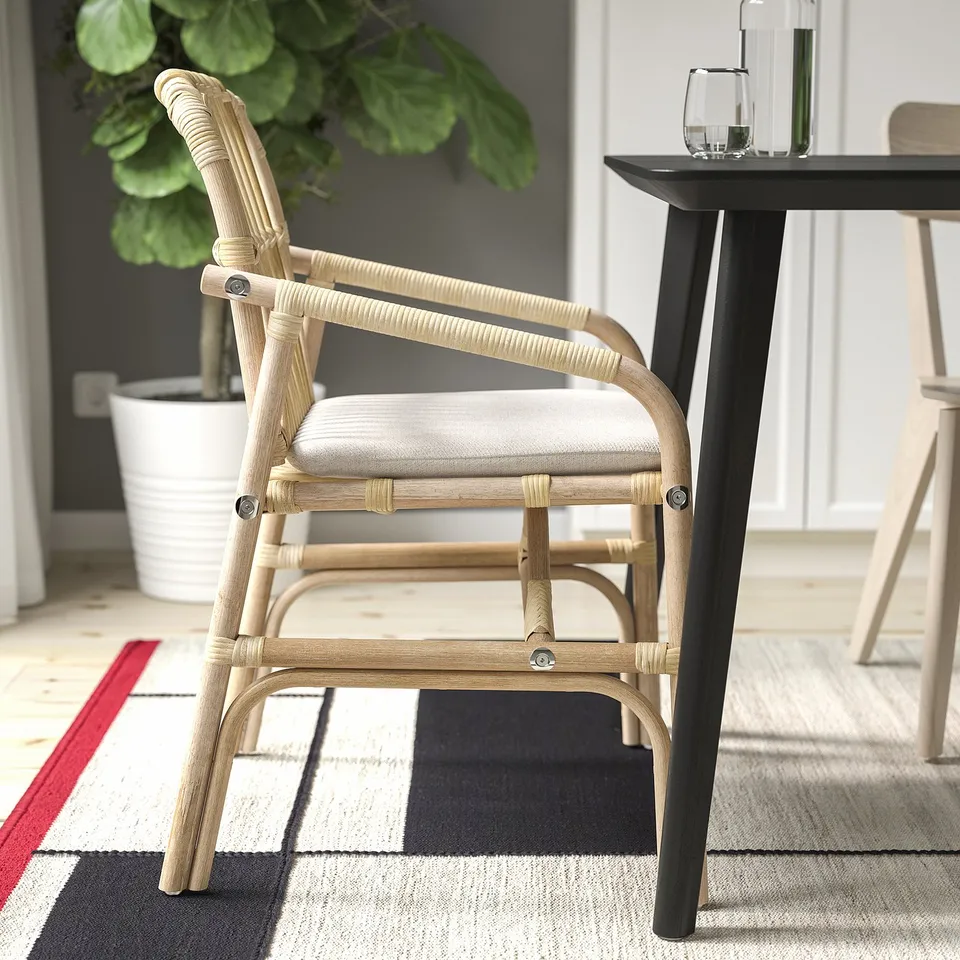 A light wooden chair with a cushioned seat sits on a chequered rug.