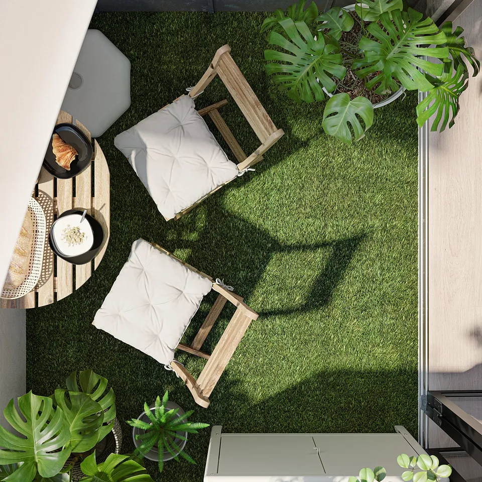 Modern balcony with green artificial turf, white furniture, and potted plants.